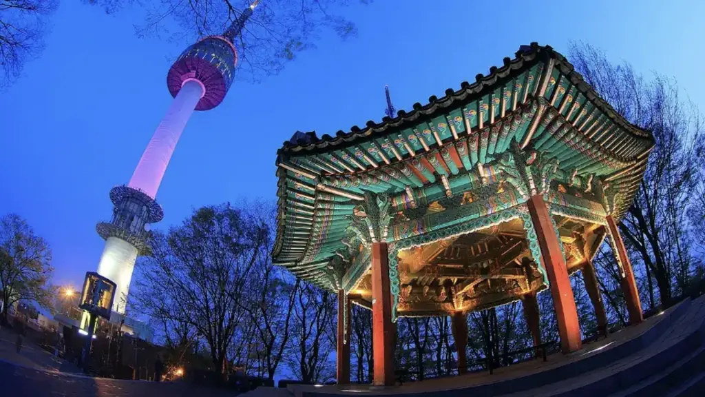 Torre N Seoul iluminada ao lado de um pavilhão tradicional
