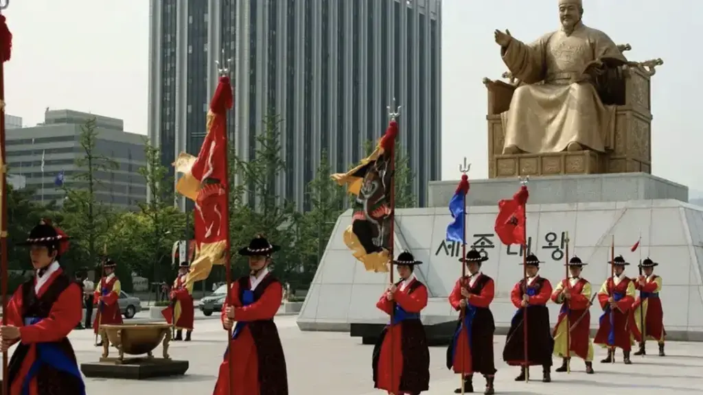 Estátua dourada do rei Sejong na praça Gwanghwamun, com a guarda em trajes tradicionais